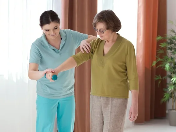 A licensed physical therapist supporting a patient practicing standing and stepping after a stroke